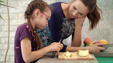 女孩吃苹果妈妈。厨房女孩切割苹果刀